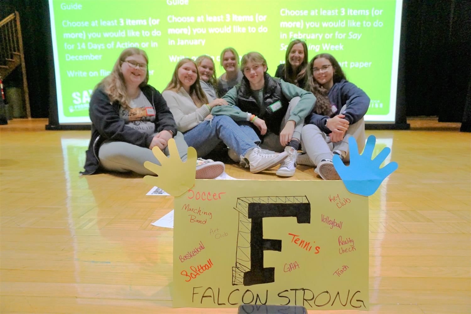  Students from SADD pose on stage behind a Falcon strong sign