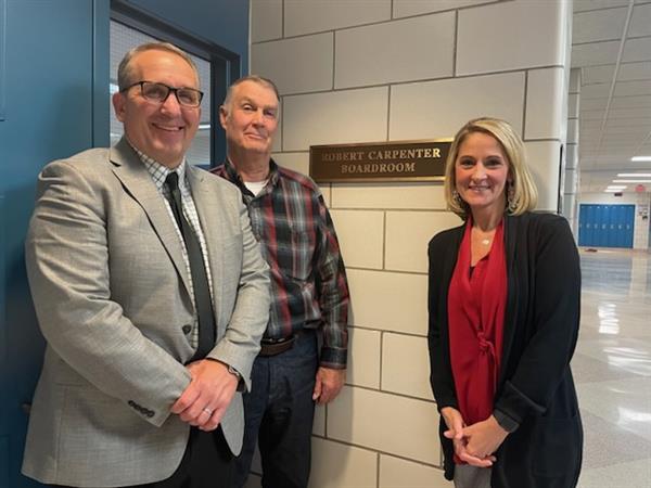 Stephen Penhollow, Robert Carpenter, and Tracy Schrader in front of the Robert Carpenter Boardroom sign.